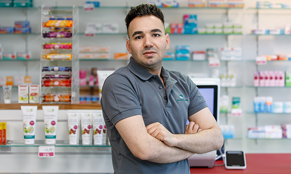 Inhaber der Petrisberg Apotheke steht vor einem Medikamentenregal in der Apotheke.