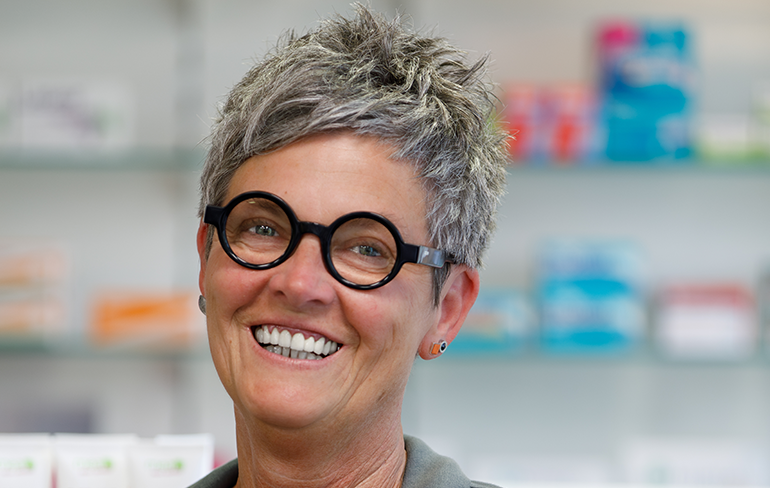 Eine Mitarbeiterin der Pluwig Apotheke lächelt in die Kamera.