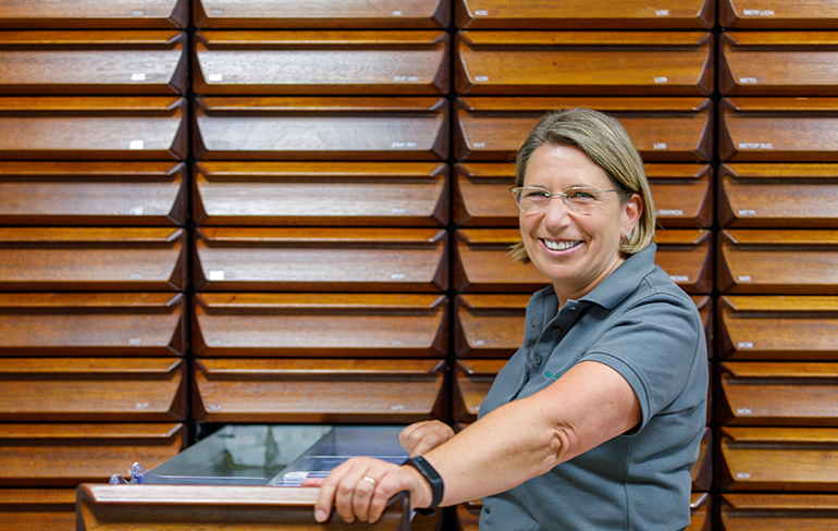 Eine Mitarbeiterin der Pluwig Apotheke steht vor einem Regal, mit ausziehbaren Schubladen.