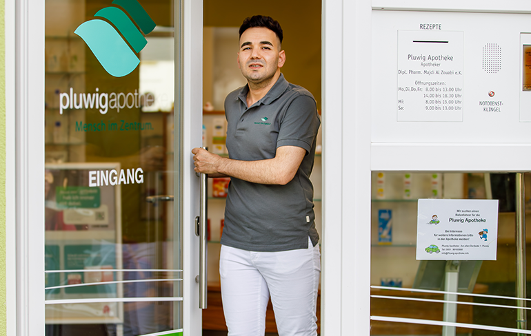 Der Inhaber der Pluwig Apotheke steht in der Tür der Apotheke.