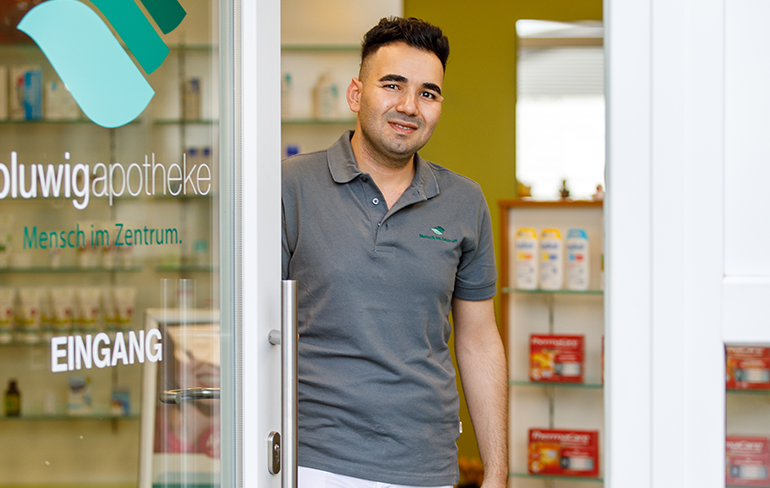 Der Inhaber der Pluwig Apotheke steht in der Tür der Apotheke.